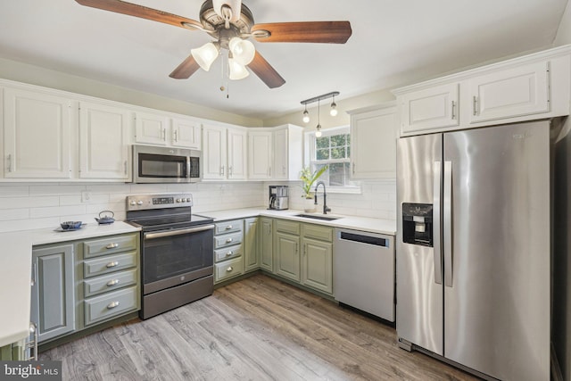 kitchen with stainless steel appliances, a sink, tasteful backsplash, light countertops, and a ceiling fan