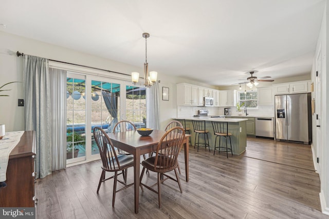 dining area with dark wood-style flooring, ceiling fan, and a chandelier