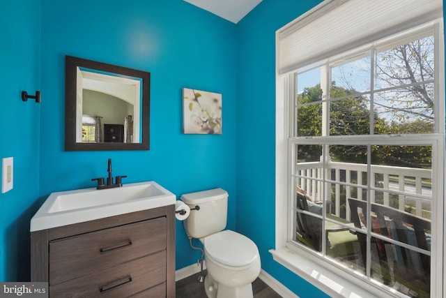 bathroom featuring toilet, vanity, baseboards, and wood finished floors
