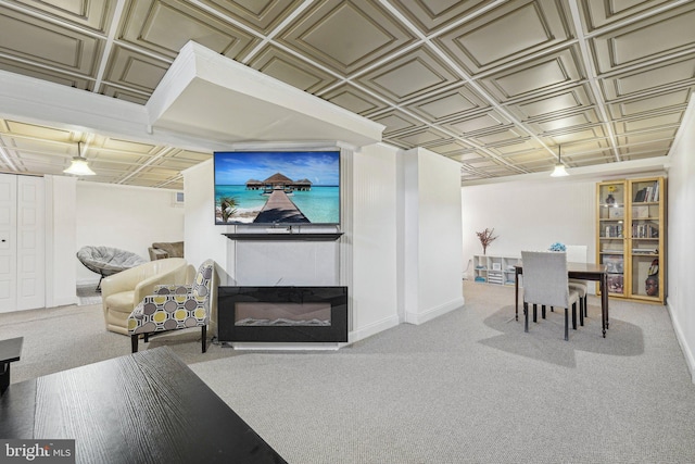 living room featuring an ornate ceiling, carpet floors, baseboards, and a glass covered fireplace