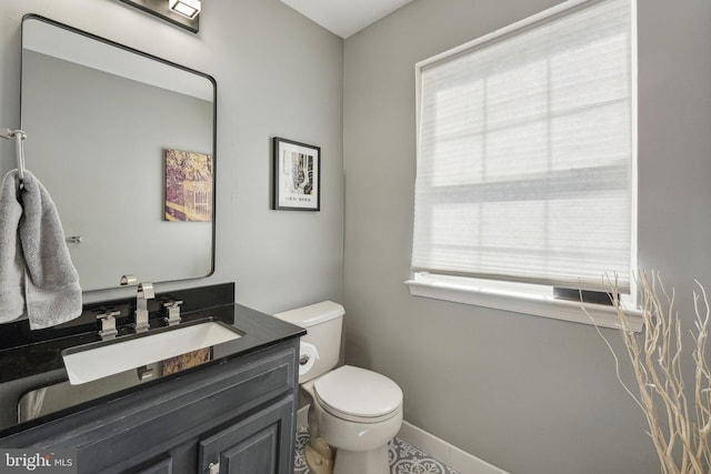 bathroom featuring healthy amount of natural light, toilet, vanity, and baseboards
