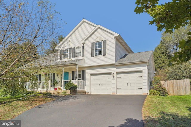 traditional-style house featuring covered porch, asphalt driveway, and a garage