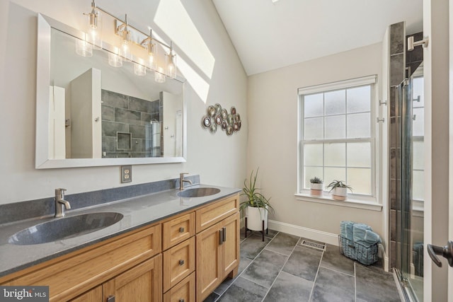 bathroom featuring vaulted ceiling, a stall shower, double vanity, and baseboards