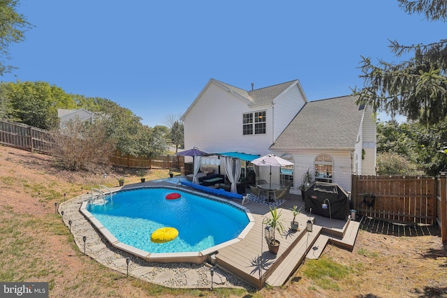 view of pool with a fenced backyard and a deck