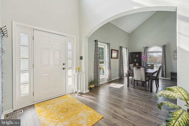 foyer entrance featuring arched walkways, high vaulted ceiling, wood finished floors, and baseboards