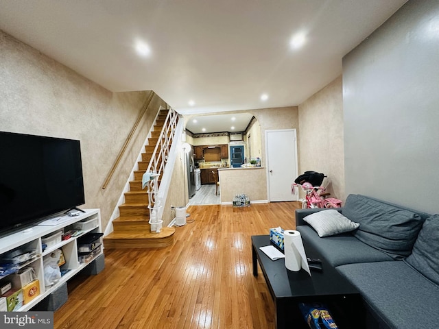 living area featuring light wood-type flooring, stairs, recessed lighting, and arched walkways