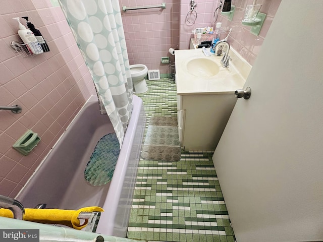 bathroom featuring tile patterned flooring, tile walls, vanity, and shower / bath combo