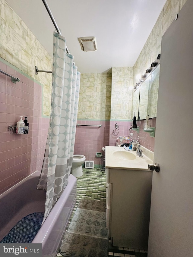 bathroom with tile walls, vanity, toilet, shower / bath combo, and tile patterned flooring