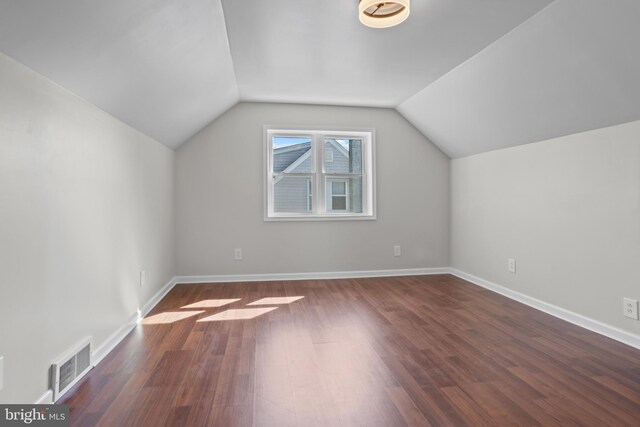 additional living space featuring dark wood-style floors, vaulted ceiling, and baseboards