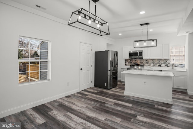 2305 James St, Baltimore, MD 21230 - kitchen with appliances with stainless steel finishes, decorative backsplash, light countertops, dark wood-style floors, and white cabinets