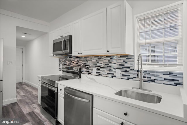 2305 James St, Baltimore, MD 21230 - kitchen featuring stainless steel appliances, decorative backsplash, white cabinetry, and dark wood-style flooring