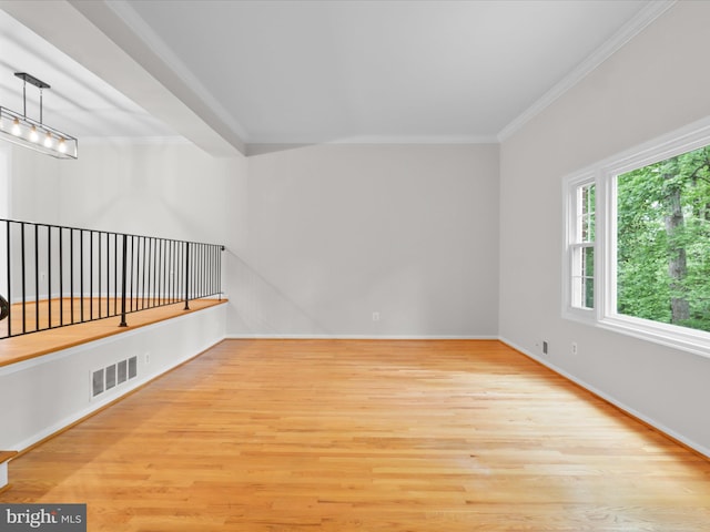 unfurnished room featuring wood finished floors, crown molding, and baseboards