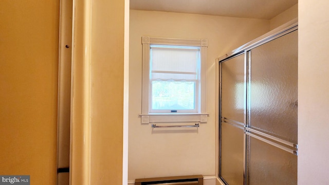 bathroom with a shower with door and baseboard heating