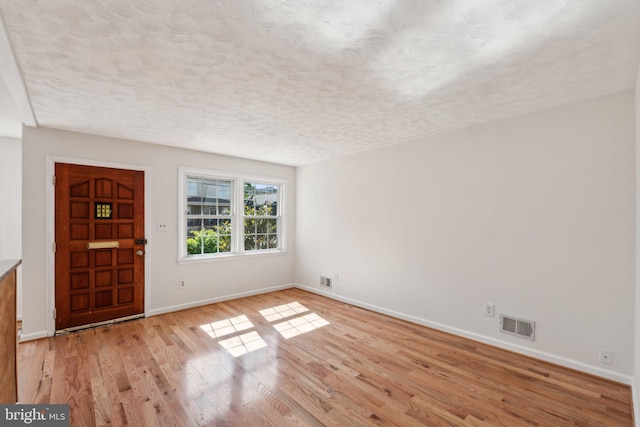 foyer featuring baseboards, a textured ceiling, and light wood-style floors