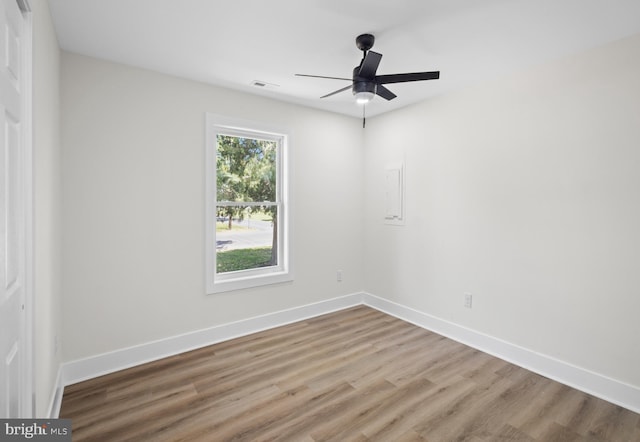 empty room featuring wood finished floors, a ceiling fan, and baseboards