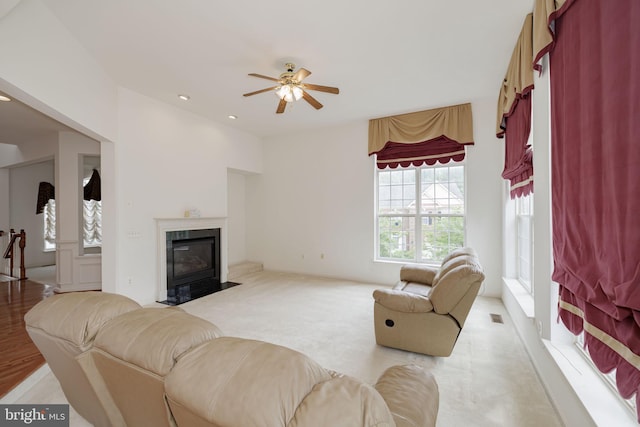 living area with ceiling fan, a fireplace with flush hearth, and recessed lighting