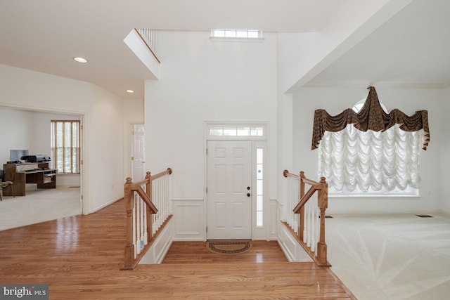 foyer entrance with light wood-style flooring, recessed lighting, and light colored carpet