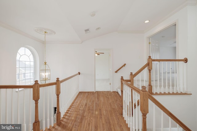 hall with an upstairs landing, light wood-style floors, lofted ceiling, ornamental molding, and a chandelier