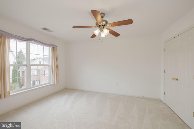 spare room with light carpet, ceiling fan, and baseboards