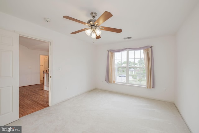 empty room featuring carpet floors, ceiling fan, and a smoke detector