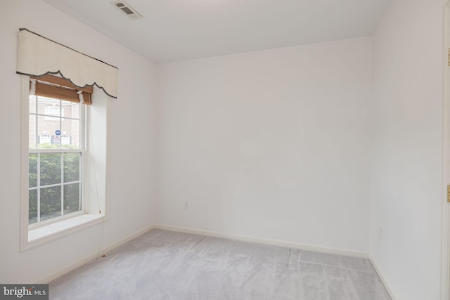 spare room featuring light carpet and baseboards