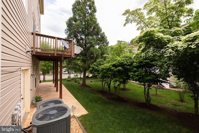 view of grassy yard featuring central air condition unit and a deck