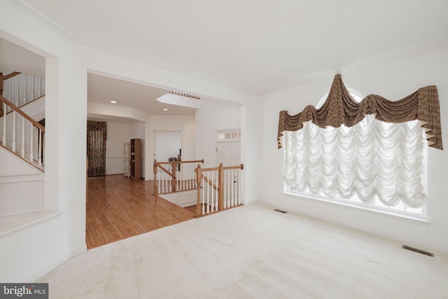 empty room featuring crown molding, wood finished floors, and carpet flooring