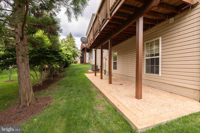 view of green lawn with a patio and central AC