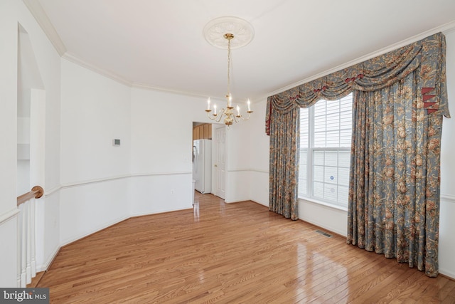 unfurnished dining area with a chandelier, light wood-type flooring, and crown molding