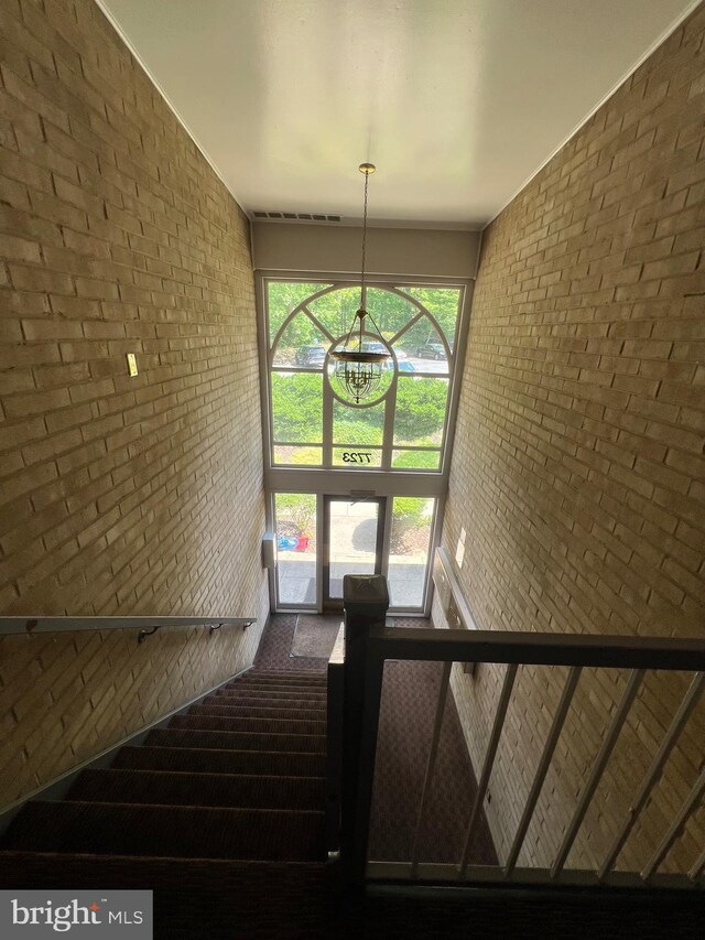 stairs with brick wall and a chandelier