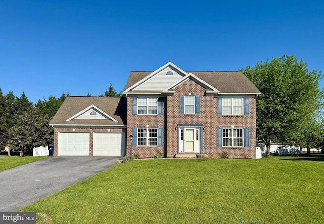 colonial inspired home featuring asphalt driveway, an attached garage, brick siding, and a front lawn