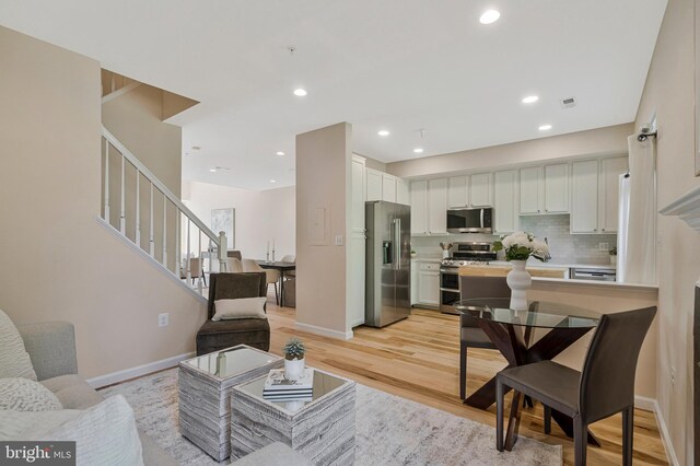 living area featuring stairway, light wood finished floors, baseboards, and recessed lighting