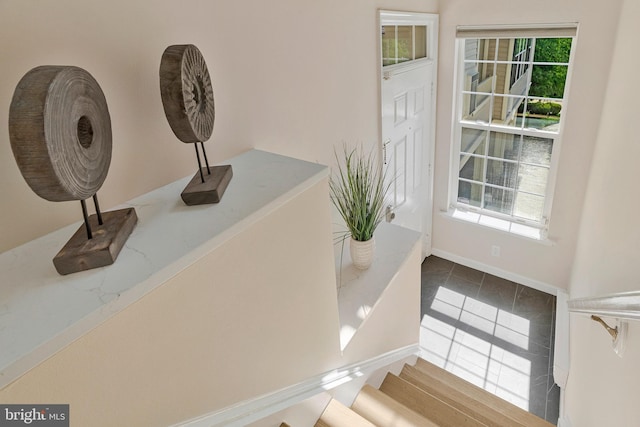 entryway with plenty of natural light, tile patterned floors, baseboards, and stairway