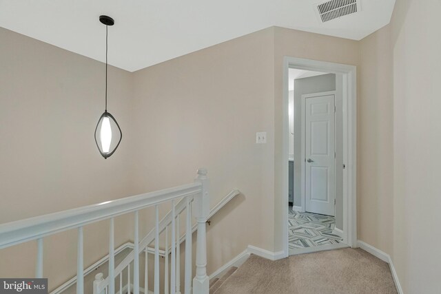 hallway featuring an upstairs landing, carpet floors, and baseboards