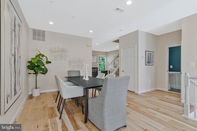 dining area with light wood-type flooring, stairs, recessed lighting, and baseboards
