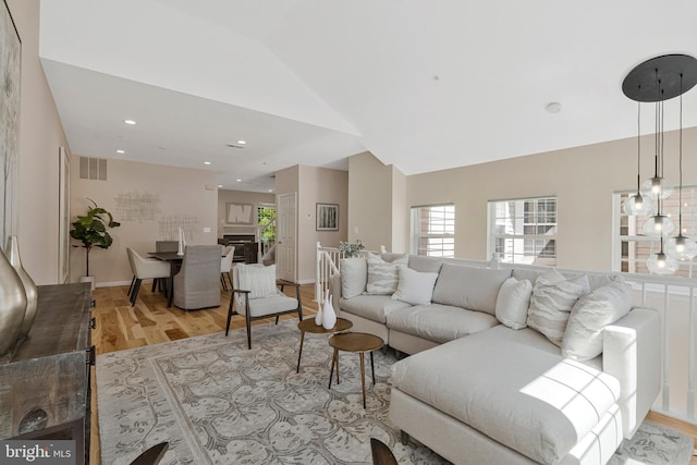 living area featuring light wood finished floors, plenty of natural light, vaulted ceiling, and recessed lighting