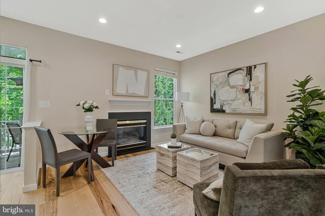 living room featuring light wood finished floors, recessed lighting, a fireplace with flush hearth, and baseboards