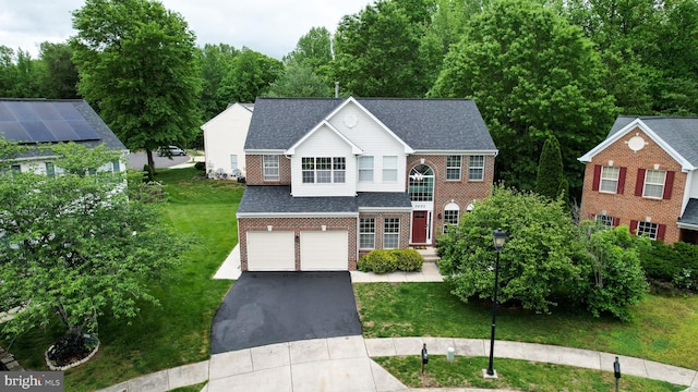 view of front of home featuring brick siding, driveway, an attached garage, and a front lawn
