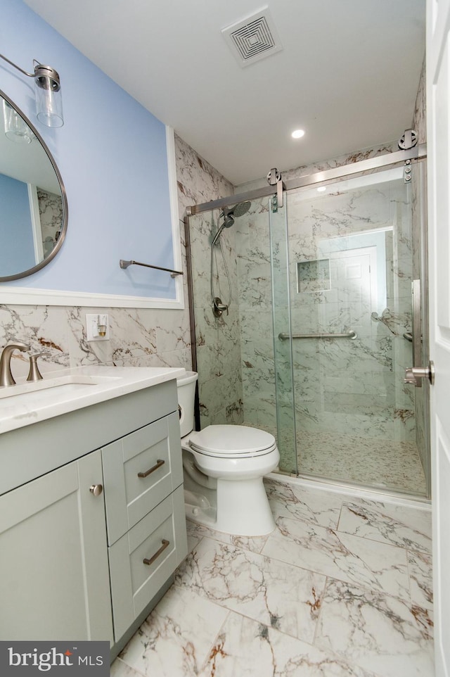 bathroom with a marble finish shower, vanity, toilet, marble finish floors, and tile walls