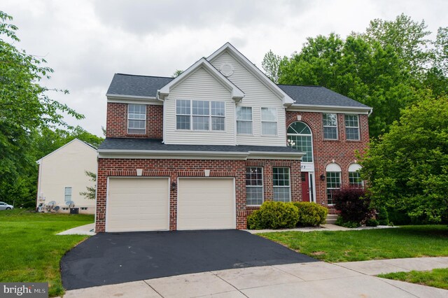 view of front of property with an attached garage, driveway, a front lawn, brick siding, and a shingled roof