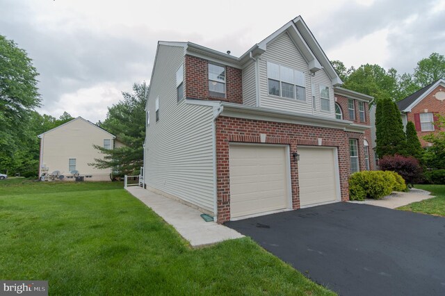 view of side of home with a garage, asphalt driveway, a yard, and brick siding