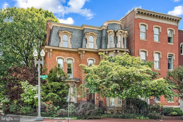 view of front of home with mansard roof, a high end roof, and brick siding