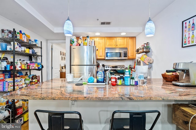 kitchen featuring appliances with stainless steel finishes, a kitchen bar, light brown cabinetry, decorative light fixtures, and recessed lighting