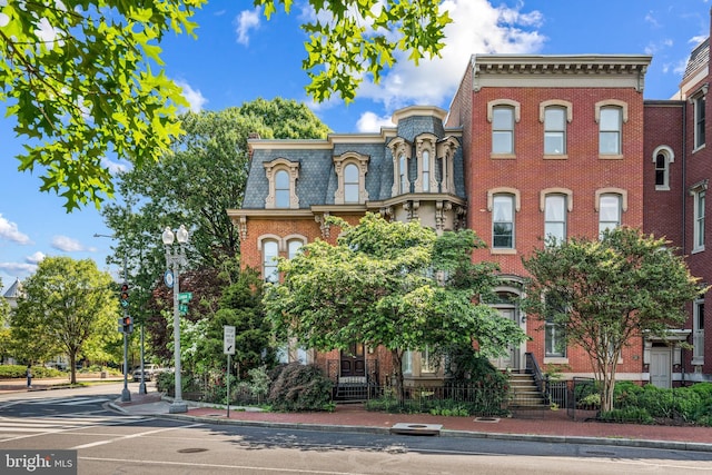 view of front of property featuring brick siding and mansard roof