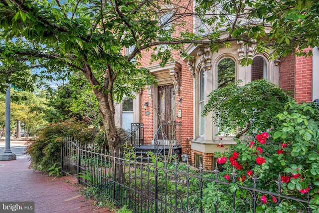 view of exterior entry with brick siding and fence