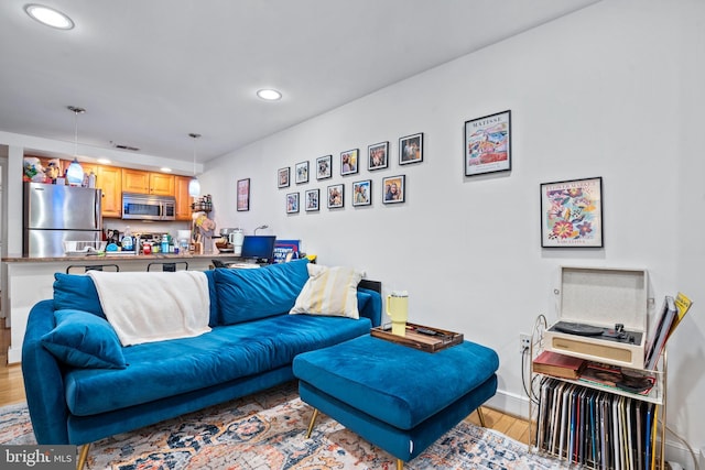 living room with light wood-style floors, recessed lighting, and baseboards