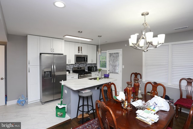 dining room featuring a chandelier, light marble finish flooring, and baseboards