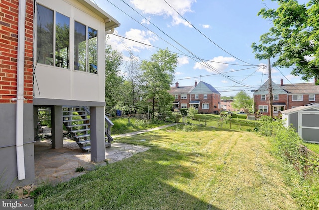 view of yard featuring stairs, a shed, an outdoor structure, and a residential view