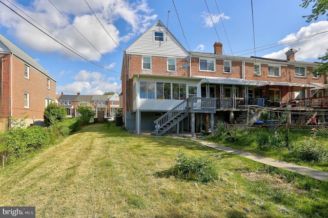 rear view of property with stairway, a sunroom, a lawn, brick siding, and a chimney