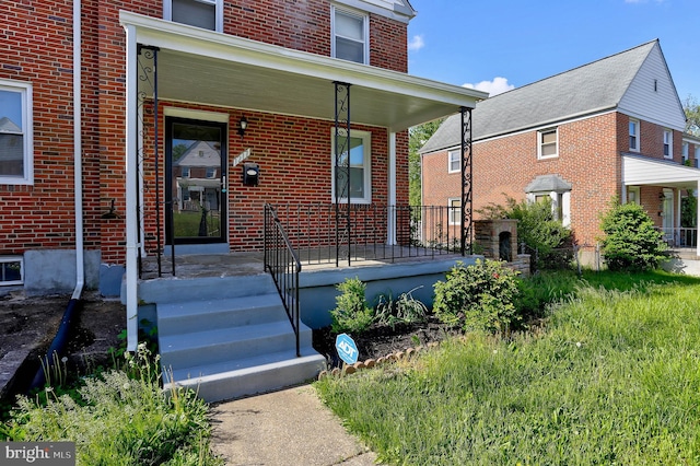 view of exterior entry featuring a porch and brick siding